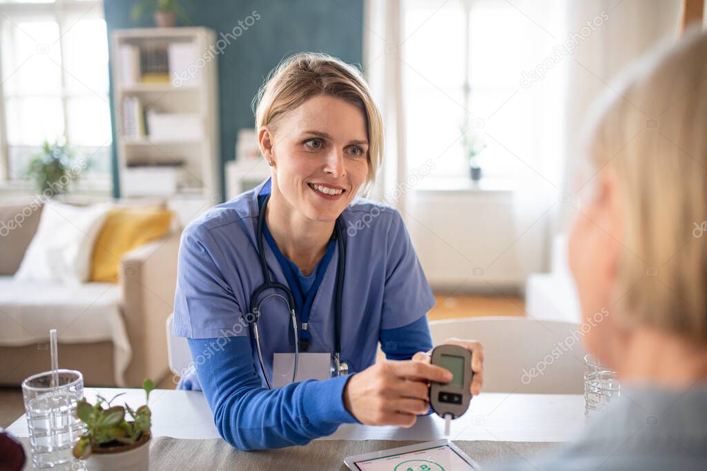 Caregiver or healthcare worker with senior woman patient, measuring blood glucose indoors.