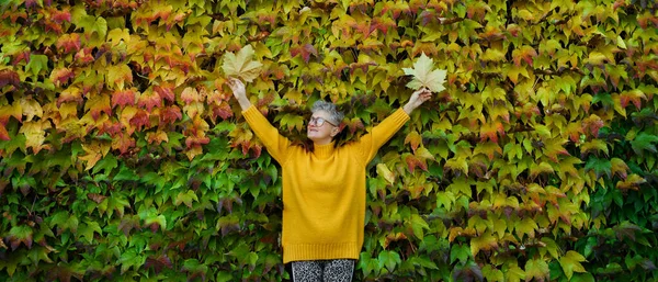 화려 한 자연의 가을 배경을 등지고 서서 팔을 벌리고 있는 나이든 여자. — 스톡 사진