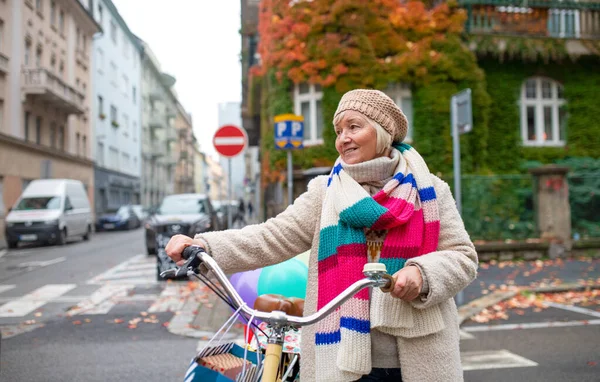 市内の屋外で自転車の交差点道路を持つシニア女性. — ストック写真