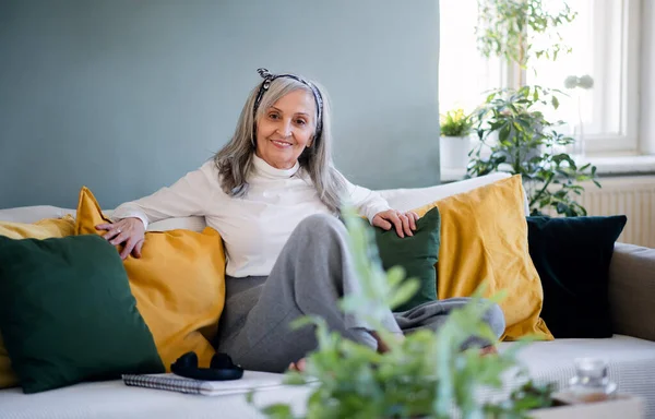 Porträtt av äldre kvinna sitter inomhus på soffan hemma, avkopplande. — Stockfoto