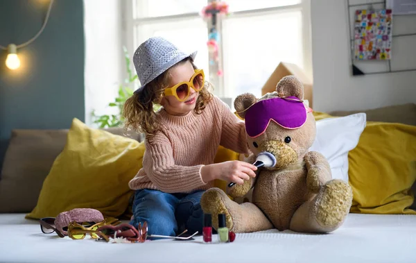 Small girl indoors at home, playing with teddy bear. Lockdown concept. — Stock Photo, Image