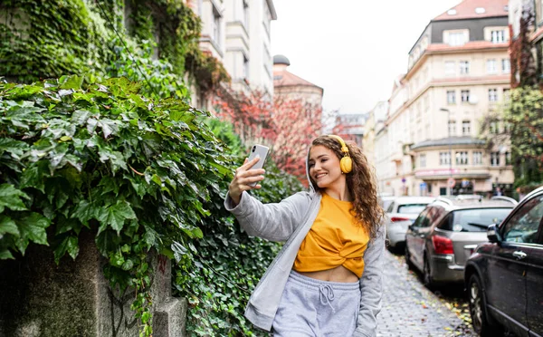 Mladá žena s chytrým telefonem venku na ulici, video pro koncept sociálních médií. — Stock fotografie