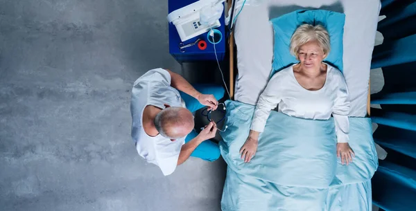 Vue du dessus du médecin avec stéthoscope examinant le patient au lit à l'hôpital. Espace de copie. — Photo