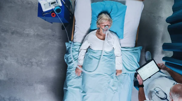 Vedere de sus a medicului și pacientului covid-19 cu mască de oxigen în pat în spital, conceptul de coronavirus . — Fotografie, imagine de stoc