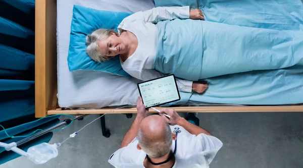 Vue du dessus du médecin avec comprimé examinant le patient au lit à l'hôpital. Espace de copie. — Photo