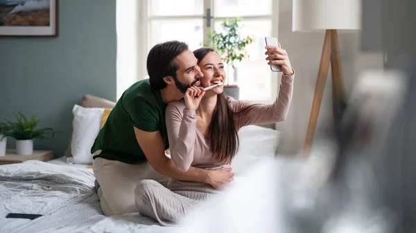 Jong paar het nemen van selfie op bed binnen thuis. — Stockfoto