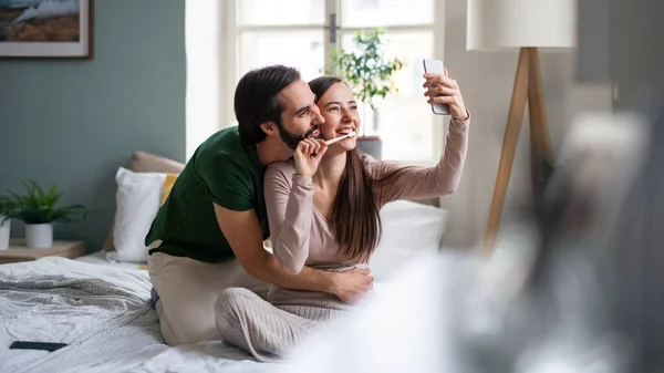 Unga par tar selfie på sängen inomhus. — Stockfoto