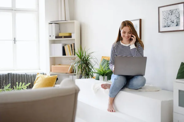 Joven estudiante con laptop y smartphone trabajando en casa, concepto coronavirus. —  Fotos de Stock