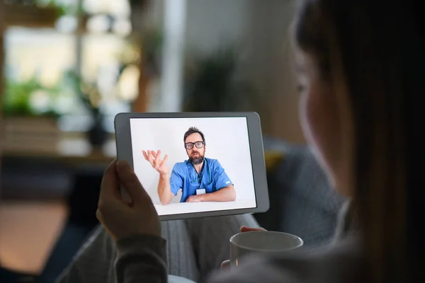 Mujer joven teniendo videollamada con el médico en la tableta en casa, concepto de consulta en línea. — Foto de Stock
