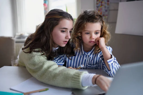 Hermanas colegialas aprendiendo en línea en el interior de casa, concepto coronavirus. — Foto de Stock