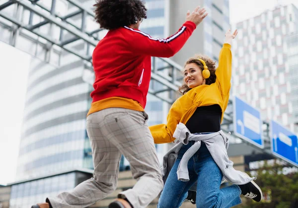 Pareja joven con smartphone haciendo video para redes sociales al aire libre en la calle, saltando. —  Fotos de Stock