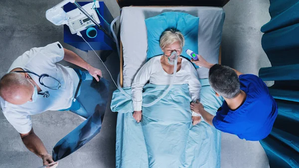 Vista superior de los médicos y paciente covid-19 con máscara de oxígeno en la cama en el hospital, concepto coronavirus. —  Fotos de Stock