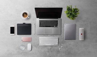 Üst kattaki ofis masasında dizüstü bilgisayarla çalışma alanı ve gri arka planda malzemeler vardı..