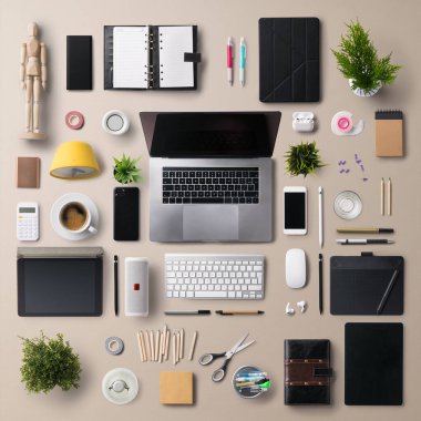 Üst düzey ofis masası, gri arka planda dizüstü bilgisayar ve ofis malzemeleriyle çalışma alanı olarak yatıyordu..