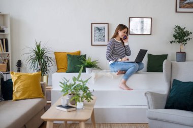 Bilgisayarı ve akıllı telefonu olan genç bir öğrenci evde çalışıyor. Mesafe öğrenme konsepti..