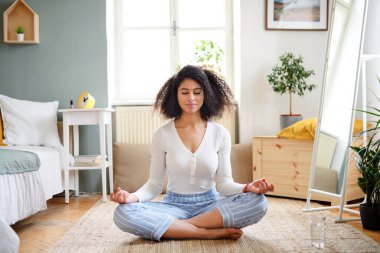 Evde yoga yapan genç bir kadının portresi..