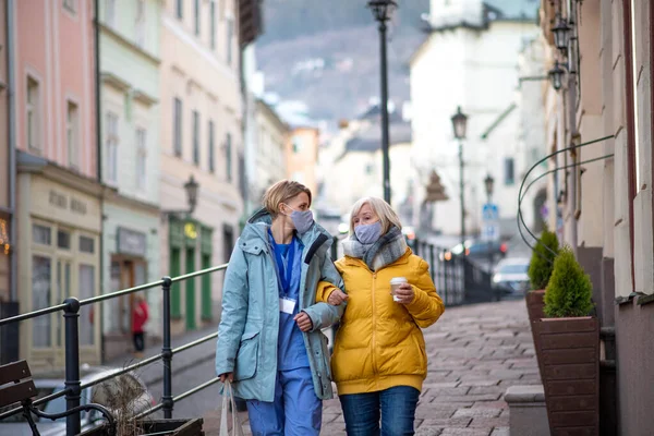町の散歩中に屋外で介護者とシニア女性,コロナウイルスの概念. — ストック写真
