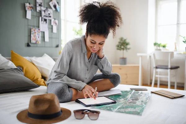 Молодая женщина с планшетом и карта в помещении дома, планируя путешествие. — стоковое фото