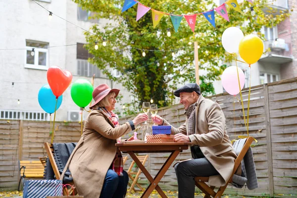 Feliz pareja de ancianos con vino en la cafetería al aire libre en la ciudad, celebrando el cumpleaños. — Foto de Stock