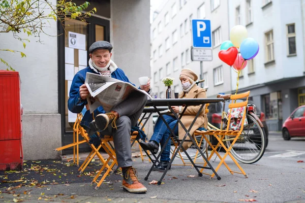 Старшие люди, сидящие в кафе на открытом воздухе в городе, коронавирусная концепция. — стоковое фото