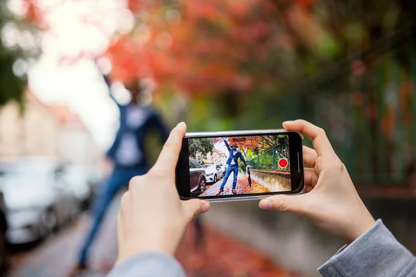 路上で屋外ソーシャルメディアのためのビデオを作るスマートフォンを持つ若いカップル. — ストック写真