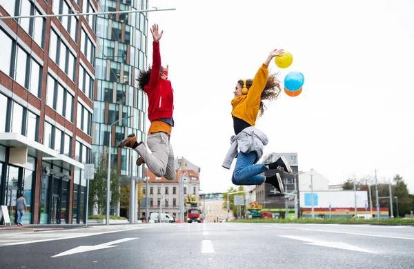 Pareja joven con globos saltando al aire libre en la calle, video para concepto de redes sociales. —  Fotos de Stock