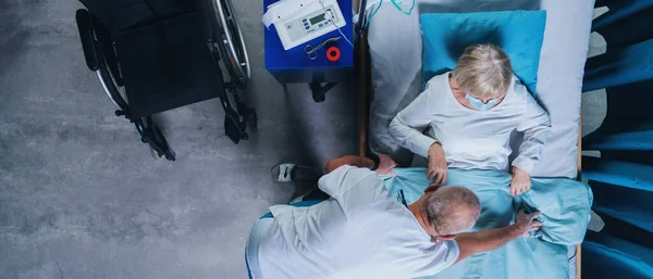 Widok lekarza kładącego pacjenta z wiremią w łóżku w szpitalu, koncepcja koronawirusa. — Zdjęcie stockowe