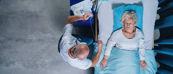 Widok lekarza i kobiety z kroplówką w łóżku w szpitalu. — Zdjęcie stockowe
