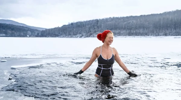 Widok z przodu aktywnej starszej kobiety w stroju kąpielowym na zewnątrz w wodzie w zimie, koncepcja zimnej terapii. — Zdjęcie stockowe