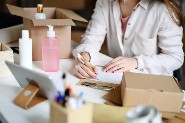 Mujer irreconocible dropshipper que trabaja en casa, paquetes de embalaje. Concepto de Coronavirus. — Foto de Stock