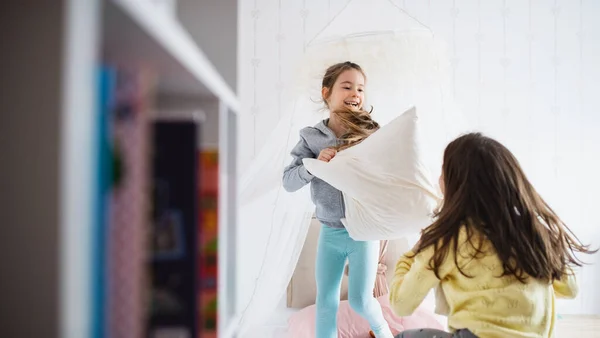 二人の小さな女の子姉妹屋内で自宅で、枕の戦いでベッドルーム. — ストック写真