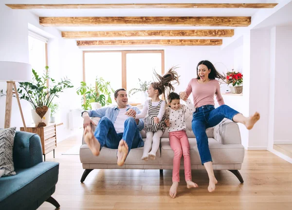 Rodiče s malými dcerami doma, baví se na pohovce. — Stock fotografie