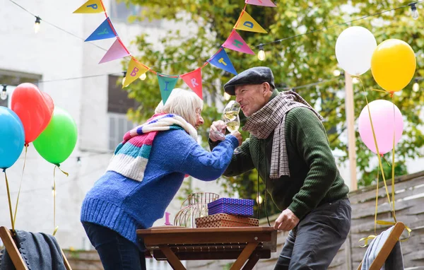 Счастливая пожилая пара с вином в кафе на открытом воздухе в городе, отмечая день рождения. — стоковое фото
