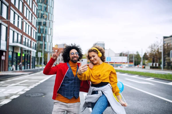 Jovem casal com smartphone fazendo vídeo para mídias sociais ao ar livre na rua. — Fotografia de Stock