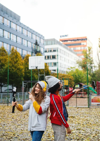 Unga par med smartphone gör video för sociala medier utomhus i stadsparken. — Stockfoto