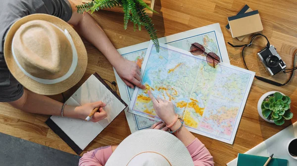 Vista superior de la pareja joven con mapas de planificación de vacaciones viaje vacaciones, concepto de viaje de escritorio. — Foto de Stock