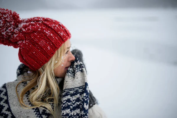 Portrait of senior woman with hat and mittens outdoors standing in snowy nature. — Stock Photo, Image