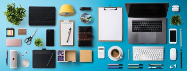 Düz yatıyordu üst görünüm ofis masası çalışma alanı dizüstü bilgisayar ve malzemeler mavi arka planda.