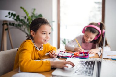 Evde dizüstü bilgisayarı olan iki liseli kız kardeş uzaktan öğrenim görüyor..