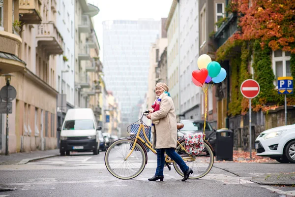 Старшая женщина с велосипедным переходом через дорогу на открытом воздухе в городе. — стоковое фото