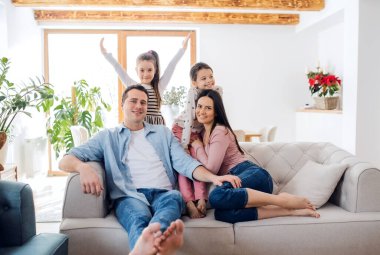 Küçük kızları olan ebeveynler evdeki kanepede oturup rahatlıyorlar..