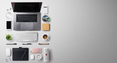 Üst kattaki ofis masasında dizüstü bilgisayarla çalışma alanı ve gri arka planda malzemeler vardı..