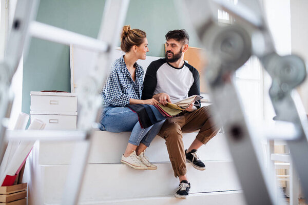 Средние взрослые пары с цветными образцами в помещении дома, переселение и diy концепции.