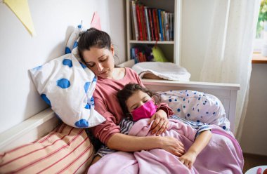 Evde hasta küçük kızına bakmaktan yorgun bir anne, koronavirüs konsepti..