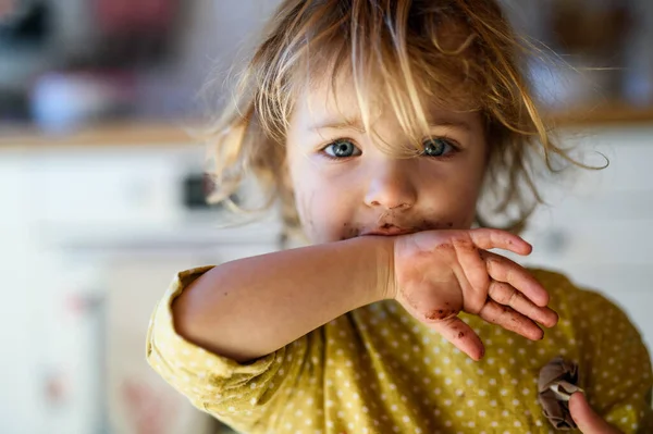 Kleines Mädchen mit schmutzigem Mund drinnen in der Küche zu Hause und schaut in die Kamera. — Stockfoto