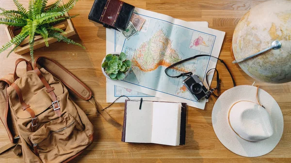 Flat lay top view desktop travel concept with laptop, maps and other travel essentials.