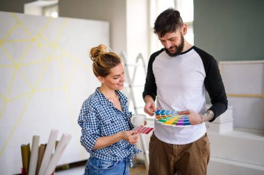 Evde renk örnekleri olan orta yaşlı çiftler, taşınma ve sönme konsepti..