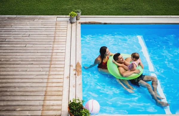 Vue du dessus de la jeune famille avec petite fille dans la piscine extérieure. — Photo