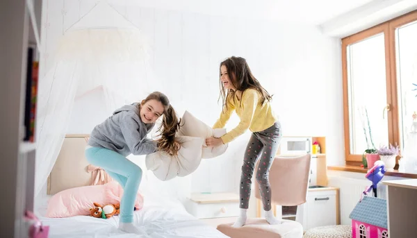 Duas meninas pequenas irmãs dentro de casa, travesseiro luta no quarto. — Fotografia de Stock