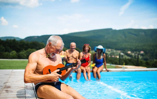 Skupina veselých seniorů u bazénu venku ve dvoře, party koncept. — Stock fotografie